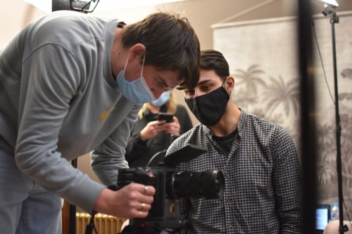 Two people filming wearing PPE masks