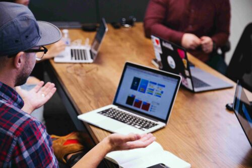 A team discusses TikTok content strategy, with laptops showing digital dashboards in a collaborative setting.